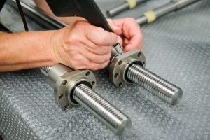 Technicien inspectant une vis à billes pour réparation express en maintenance industrielle